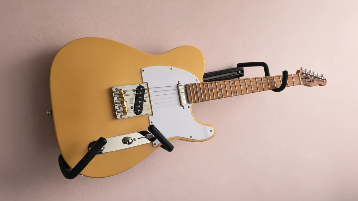 Completed butterscotch T-style guitar mounted against a pale workshop wall